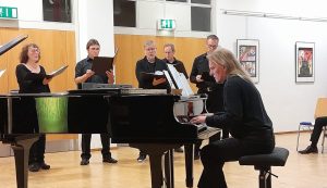 Bernhard Stephan am Klavier mit Chor im Hintergrund